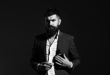 Siyah arka planda konyak içmeye hazır takım elbiseli ciddi bir yüz ile iş adamı. Sommelier alkol tatma sakallı. Parti ve kavram içme
