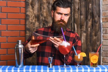 Sakallı ve sert yüzlü barmen kokteyl yapar..