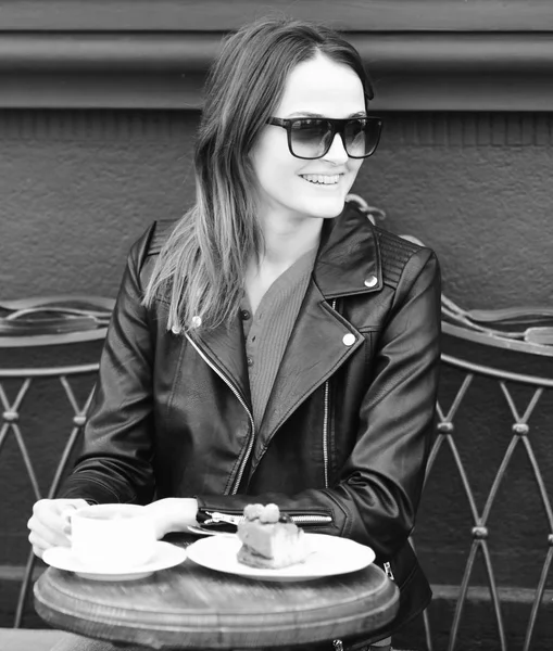 Chica cerca de sabroso pastel de bayas y café en la mesa en el fondo de la terraza marrón. La señora bebe café durante el descanso del café. Confitería y estilo urbano —  Fotos de Stock