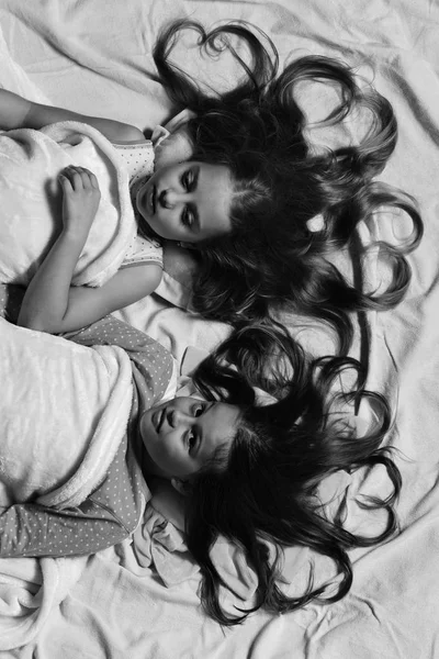 Pijama partisi ve çocukluk kavramı. Kızlar yalan beyaz ve pembe çarşaf üzerine — Stok fotoğraf