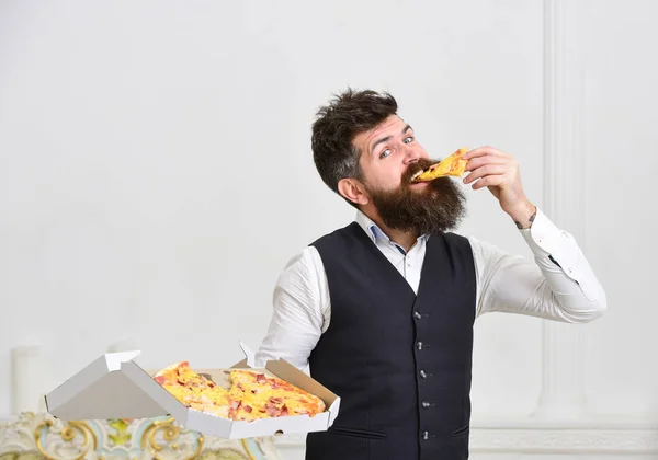 Conceito de entrega de pizza. Macho em roupas clássicas com fome, detém fatia de pizza de queijo, come, fundo branco. Homem com barba e bigode segura caixa entregue com pizza quente fresca saborosa — Fotografia de Stock