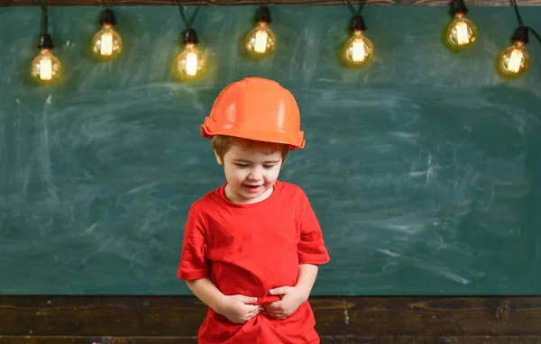 귀여운 소년 입고 오렌지 헬멧입니다. 아래쪽으로 보고 웃는 아이. — 스톡 사진