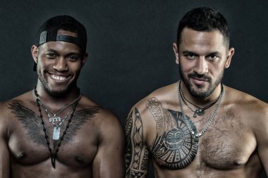 Afrika insan ve dövmeli beyaz adam gülümseyen modelleri moda. Siyah arka plan üzerine vücut geliştiriciler. Sporcular ile seksi torsolar, vücut bakımı ve fitness kavramı. Moda modelleri moda aksesuarları