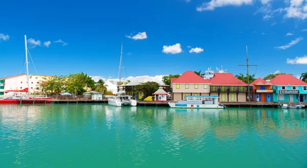 St johns, Antigua - 05 maart 2016: kade met huizen en jachten in de turquoise zee op blauwe hemel. Reizen en wanderlust. Zomervakantie op tropisch eiland — Stockfoto