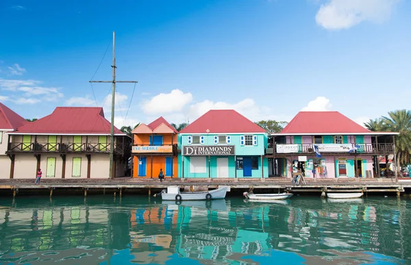 圣约翰, 安提瓜-2016年3月05日: 船停靠在海边的村庄码头, 在蓝天上的房子。热带岛的暑假。发现和冒险。流浪 — 图库照片
