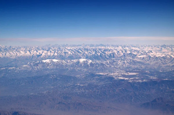 Montañas con picos nevados en el cielo azul, vista aérea. Planeta Tierra paisaje natural. Viajar alrededor del mundo. Protección del medio ambiente y ecología. El día de la Tierra es cumpleaños mundial — Foto de Stock