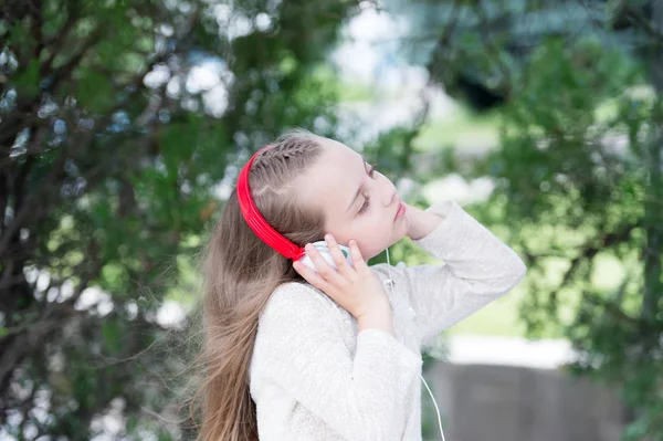 Menina ouvir música no parque de verão. Som melódico e mp3. Criança gosta de música em fones de ouvido ao ar livre. Criança da moda e tecnologia moderna. Férias de verão e diversão — Fotografia de Stock