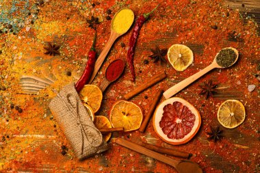 Tarçın, öğütülmüş kırmızı biber ve curcuma toz ve mutfak otlar dolu kaşık masa üzerinde dağınık. Ahşap doku baharat kaşıklarla. Baharat tüm ahşap yüzey üzerinde dağınık. Baharat kavramı