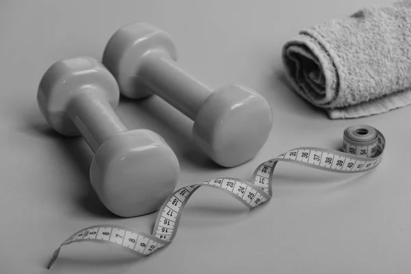 Sports regime symbols. Dumbbells in green color, twisted measure tape