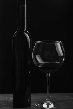 Siyah arka planda cam kenarında bir şişe şarap.