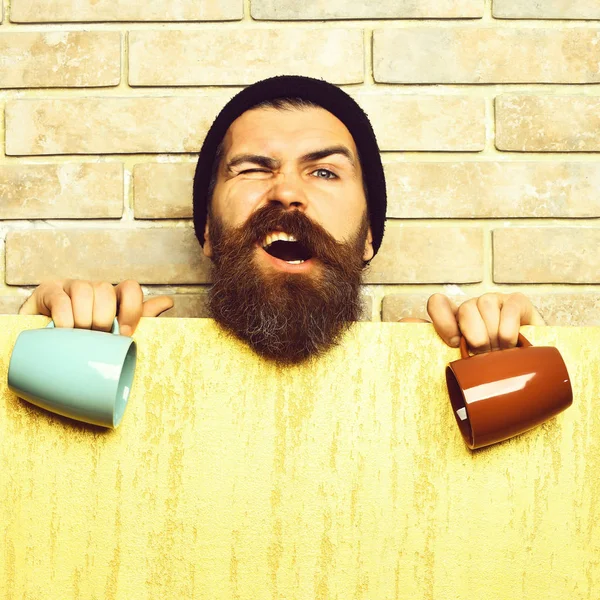 Barbudo brutal hipster caucásico con hoja de papel y tazas —  Fotos de Stock