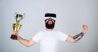 Sanal başarı kavramı. Şampiyonluğa ulaştı, Vr gözlüklü elinde altın kadehi tutun. Vr bardaklarda sakallı adam kazanan, gri arka plan var. Hipster mutlu yüz üzerinde sanal şampiyonluğa