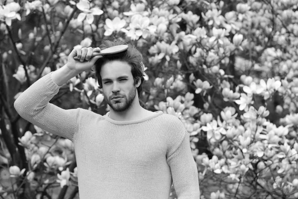 Parkta tomurcuklanan ağaçlarla saçlarını tarayan maço.