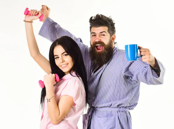 Couple plein d'énergie après les exercices du matin et le café. Joyeux couple debout et tenant une tasse de café et haltère. Concept de routine matinale — Photo