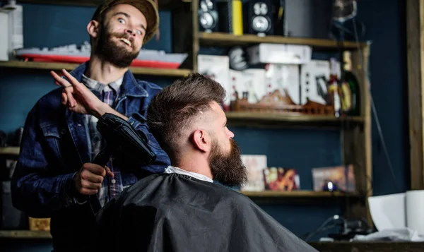 Hippi saç modeli almak istemci sakallı. Saç kurutma makinesi styling saç istemci ile neşeli yüzündeki berber. Kuaför saç kurutma makinesi ile saç modeli sakallı adam, salon arka plan için çalışır. Tasarım konsepti