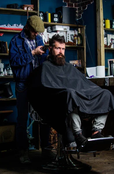 Barbiere con clipper taglio capelli su nuca di cliente. Un cliente hipster che si taglia i capelli. Concetto di acconciatura hipster. Barbiere con tagliacapelli lavora sul taglio di capelli del barbuto ragazzo barbiere sfondo — Foto Stock