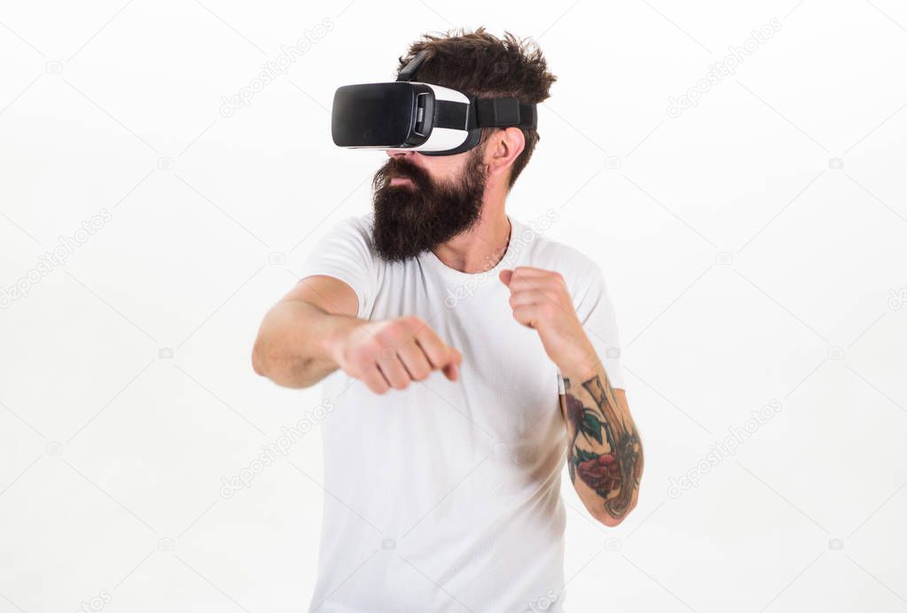 Man with beard in VR glasses fighting, white background. VR gadget concept. Guy with head mounted display fight in virtual reality. Hipster on busy face exploring virtual reality with modern gadget