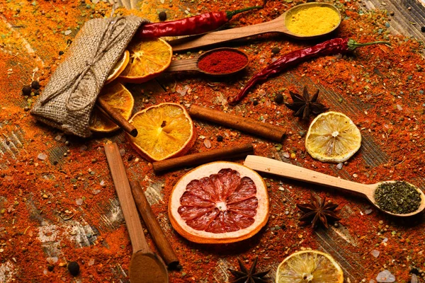 Cuillères remplies de cannelle, poivron rouge broyé et poudre de curcuma et herbes de cuisine dispersées sur la table. Concept d'épices. Épices éparpillées sur toute la surface en bois. Cuillères avec épices sur texture bois — Photo