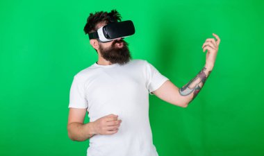 Vr gözlük, yeşil arka planda sakallı adam. Hipster gitarist hevesli yüzündeki modern teknoloji eğlence için kullanın. Vr gözlüklü öğrenin gitar müzik çalmak. VR müzisyen kavramı