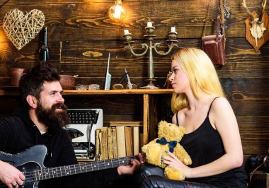 Adam oyun gitar Bayan ise oyuncak ayı elinde tutar. Çift Romantik akşam, ahşap iç arka plan geçirmek. Romantik tarih kavramı. Rahat yüzleri aşık çift romantik atmosferinin keyfini çıkarın.