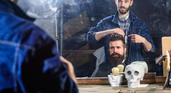 Mannen med skägg och mustasch i frisörer stol framför spegeln bakgrund. Hipster-klienten att få frisyr. Barbershop koncept. Reflexion av Frisör styling hår av skäggiga klient med kam — Stockfoto