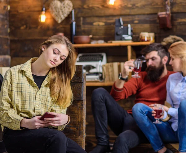 Teenage girl checking smartphone, virtual reality vs real life concept. Bearded man chatting with his blond wife while drinking wine or punch. Daughter spending time on her own without parents