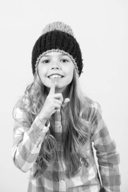 Şapkalı kız, turuncu arka planda ekose gömlekli gülümseme.