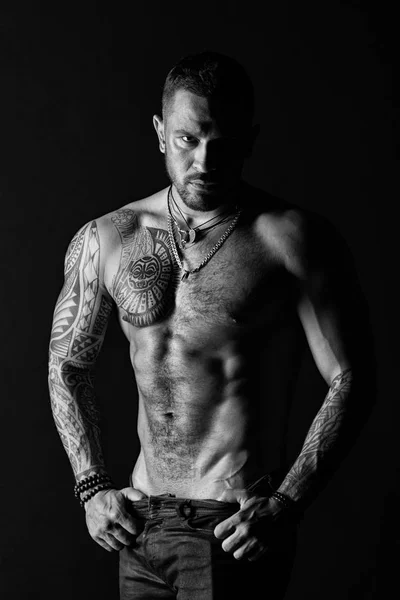 Homem de moda com tatuagem tirar jeans. Homem stripper mostrar torso sexy. Desportista com seis maços e abdominais. Atleta com músculos bíceps e tríceps. Desejo e atração, preto e branco — Fotografia de Stock