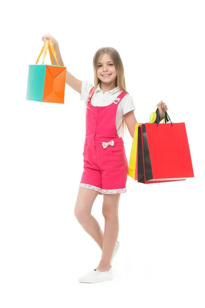 Lány vásárló mosoly táskákkal, elszigetelt fehér. Boldog gyermek tartsa bevásárló táskák. A mosolygó kis shopaholic mutatja be. Ajándékok ideje. Vásárlás és eladás — Stock Fotó