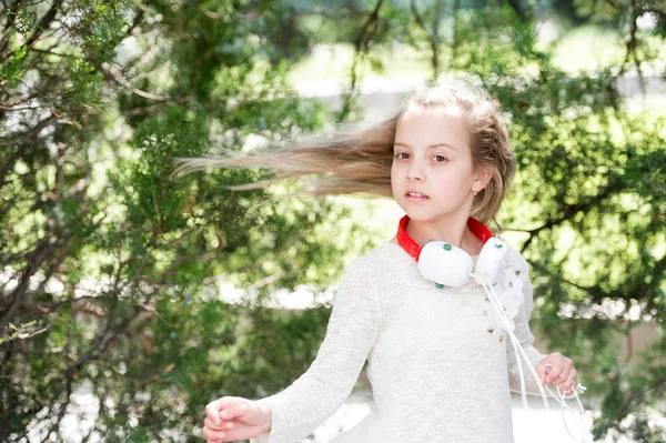 Küçük çocuk müzik kulaklık açık keyfini çıkarın. Kız dans müzik yaz Park. Çocuk dansçı ile uzun saç uçan. Melodi ses ve mp3. Yaz eğlence ve neşe — Stok fotoğraf
