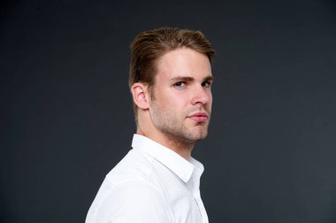 Güven ve erkeklik. Olarak, onun görünümünü kendine güvenen bir adam. Adam iyi bakımlı kıl ve saç modeli koyu arka plan ile. Maço emin katı yüz kapatın. Adam yakışıklı çekici beyaz gömlek