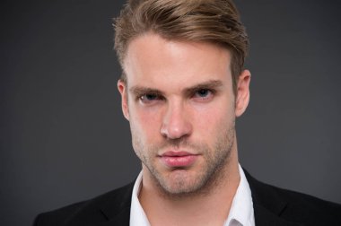 Erkeklik ve güven. Olarak, onun görünümünü kendine güvenen bir adam. Kıl ve saç modeli ile de bakımlı adam gri arka plan. Adam yakışıklı resmi takım elbise. Maço emin konsantre yüz yakın çekim