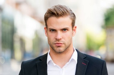 Genç ve başarılı. İşadamı yakışıklı çekici office çalışan emin yüz. Bakımlı zarif resmi takım elbise defocused kentsel arka plan yürür. İşadamı ciddi yürüyüş sırasında öğle yemeği zamanı