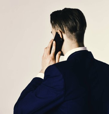 Gri arka planda cep telefonuyla konuşan adam..