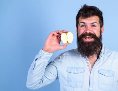 Adam gülümseyen tutan apple mavi arka plan sakallı. Yarım elma sağlıklı yaşam tarzı. Hipster doğal ekolojik elma gösterir. Besin değeri kavramı. Vitamini beslenme diyet sağlık