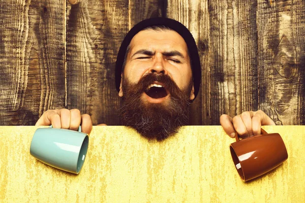 Barbudo brutal hipster caucásico con hoja de papel y tazas — Foto de Stock