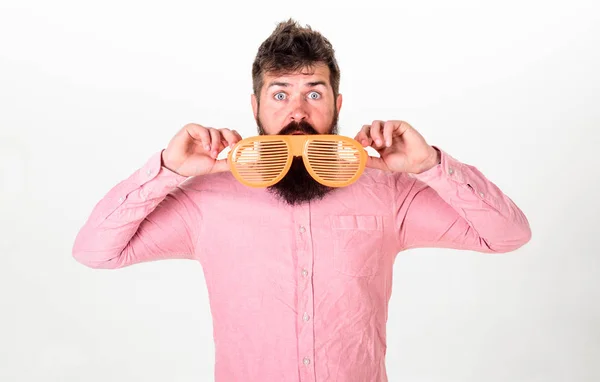 Hipster gucken aus einer riesigen gestreiften Sonnenbrille. Mann mit Bart und Schnurrbart auf dem Gesicht trägt lustige Brille, weißer Hintergrund. Typ mit Bart und Brille. Optik und Brillenkonzept — Stockfoto