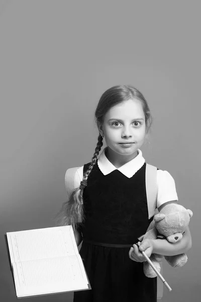 Aluno tem livro e ursinho de pelúcia. Criança de uniforme escolar — Fotografia de Stock