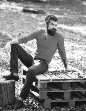 Sakallı adam ahşap paletlere oturur..