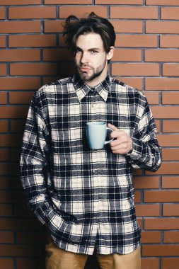 Duvarda fincanı tutan yakışıklı adam.