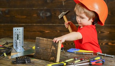 Yürümeye başlayan çocuk meşgul yüzündeki çekiç aracı evde atölye ile oynuyor. Çocuk Çocuk tamirci oynamak. Kavram handcrafting. Çocuk kask Oluşturucu veya repairer, onarımı veya handcrafting olarak oynayan sevimli içinde