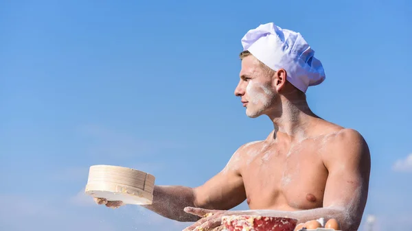 Baker working with flour and sieve, kneading dough. Hands of chef cook covered with sticky dough and flour. Man muscular baker or cook sifts flour through sieve. Pizzaiolo concept