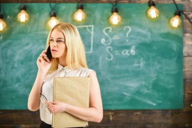 Sınıfta cep telefonu konuşurken kitap olan kadın. Öğretmen öğrencilerin hakkında rapor. Öğretmen konsantre yüzüne telefonu, arka plan kara tahta sorunlarını çözme. Mobil rapor kavramı