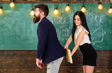Sırasında eğlenmek yüzü gülümseyerek kıza öğretmen cezalandırır. Öğrenci Bayan öğretmenler üzerinde kalça kitap ile tokat. Rol oyunları kavramı. Seksi öğrenci, kara tahta arka plan ile ceza sakallı