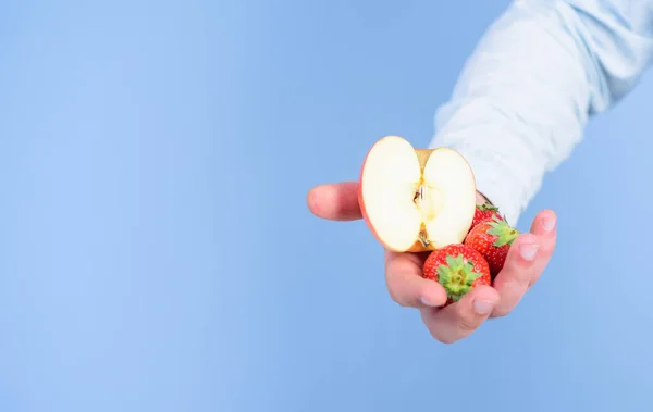 딸기와 애플 파란색 배경의 절반 남자 손. 자신을 도울. 손으로 받아 딸기와 사과 과일을 제안합니다. 잘 익은 과일의 신선한 추수입니다. 과일 유기농 치료 또는 간식 — 스톡 사진