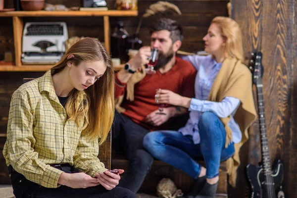 Adolescente absorbido por gadget y no hablar con los padres, brecha de generación, concepto juvenil rebelde. Barbudo hombre y mujer rubia tener encantadora charla mientras su hija está enviando mensajes de texto amigos por teléfono —  Fotos de Stock