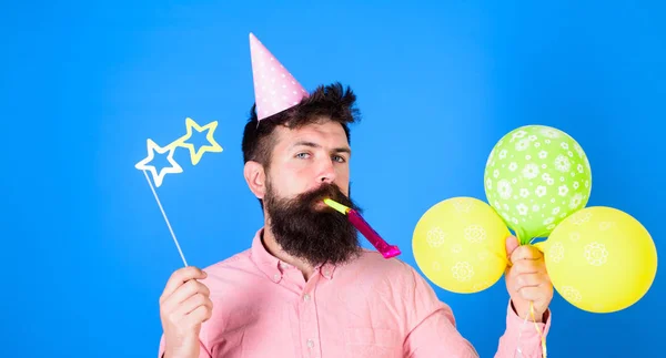 Pembe gömlek ve parti şapkası, parti horn, ıslık giyen sakallı, yakışıklı adam portresi renkli balonlar, kameraya bakıyor tutuyor. İnsanlar, kutlama kavramı — Stok fotoğraf