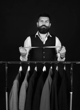 Kendine güveni olan terzi, özel ceketlerin yanında mezura tutuyor.