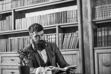 Çay bardağının yanındaki eski kafalı adam. Aristokrat gelenekleri. Aristokrat 'ın katı yüz okuma kitabı. Klasik takım elbiseli adam klasik iç mekanda, kütüphanede, arka planda kitap raflarında oturuyor..