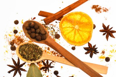 Baharat Seti kavramı. Baharat Seti pişirme veya sıcak içecekler, hazırlama kapatın. Kaşık, kurutulmuş portakal ve tarçın sopa beyaz arka plan üzerinde. Mutfak otlar ve kuru malzemeler ile baharat karışımı.